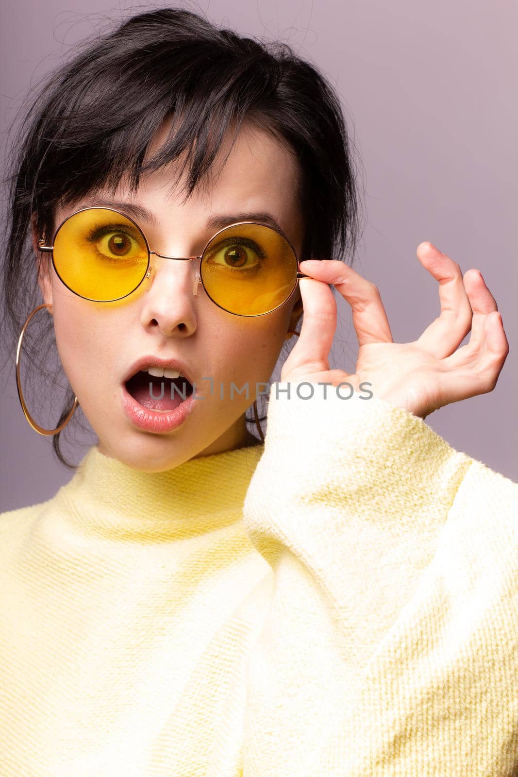 brunette woman in yellow glasses and yellow sweater, close-up portrait. High quality photo