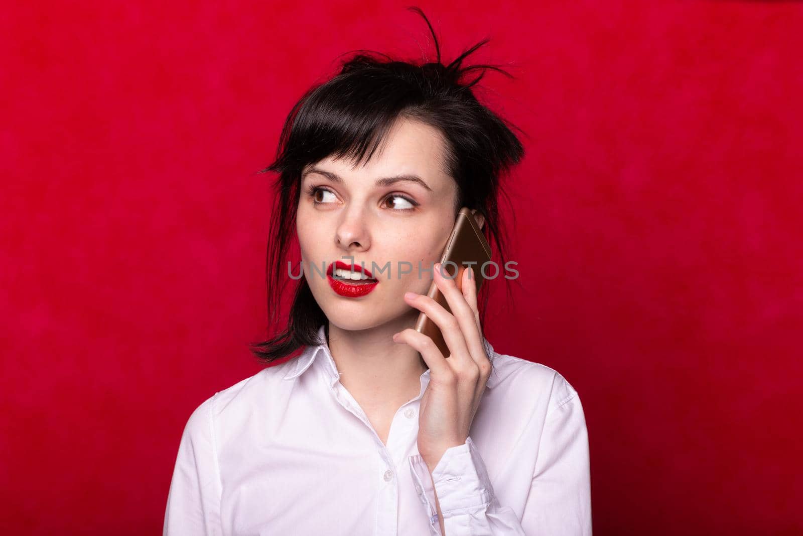 beautiful woman manager in a white shirt speaks on the phone, red lips, red background by shilovskaya