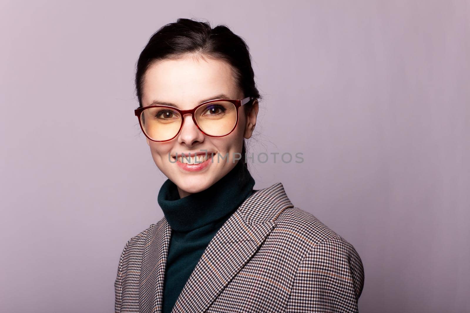 woman in a green turtleneck, jacket, glasses, portrait on a gray background. High quality photo