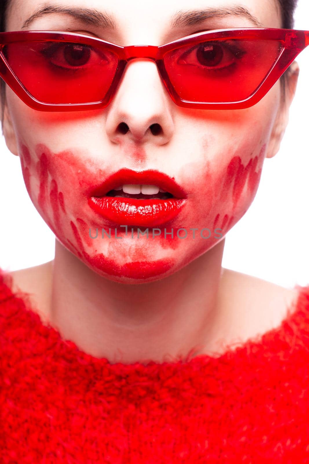 brunette woman in red glasses smears red lipstick on her face, red nails, white background. High quality photo