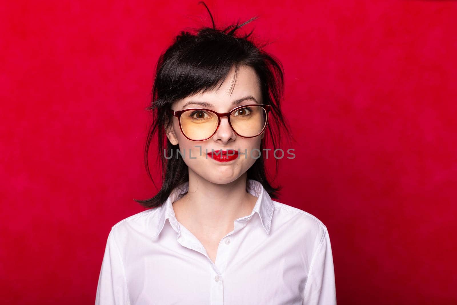 woman manager with red lips in a white shirt and glasses on a red background. High quality photo