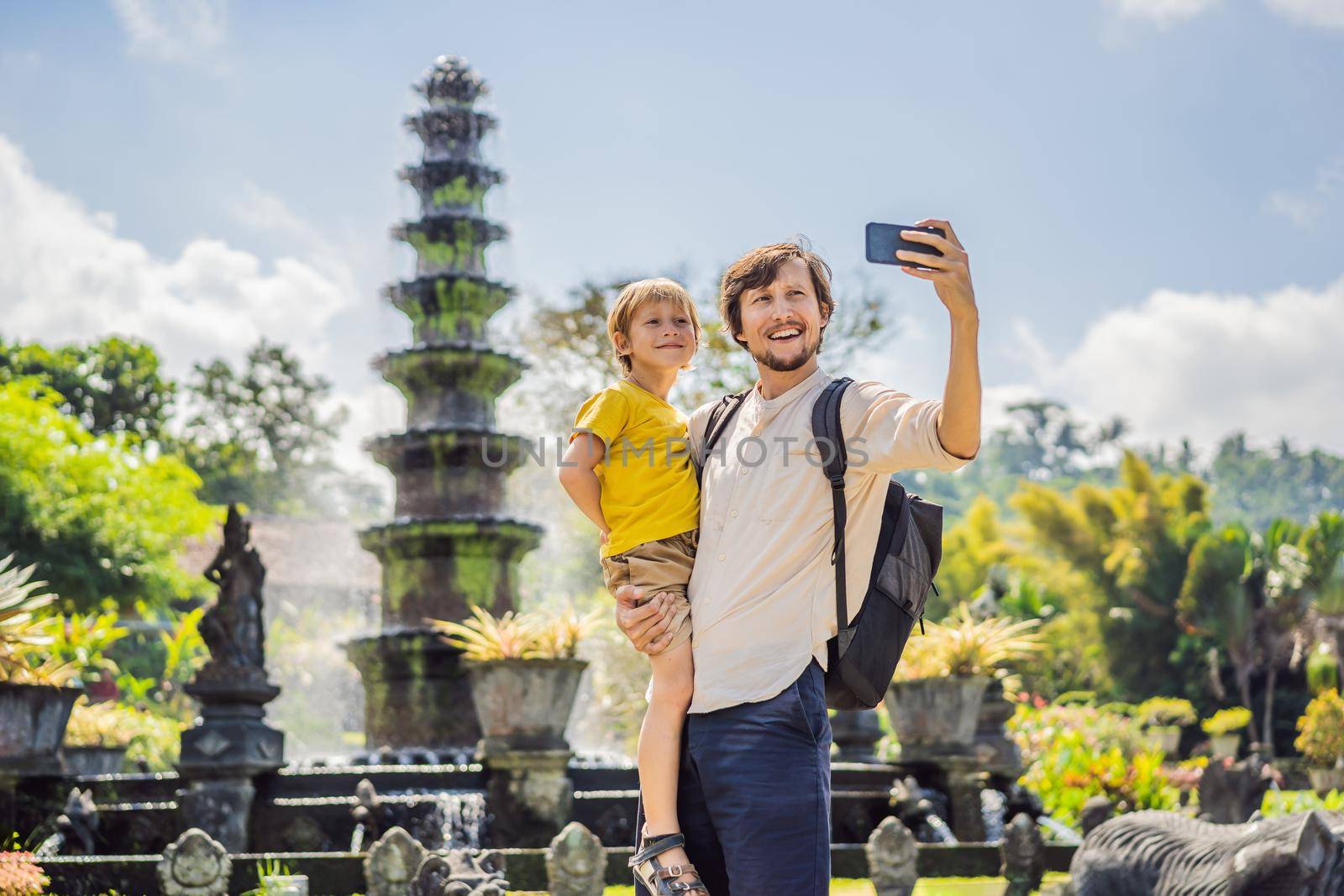 Dad and son tourists in Taman Tirtagangga, Water palace, Water park, Bali Indonesia. Honeymoon in Bali. Traveling with children concept. Kids friendly place.