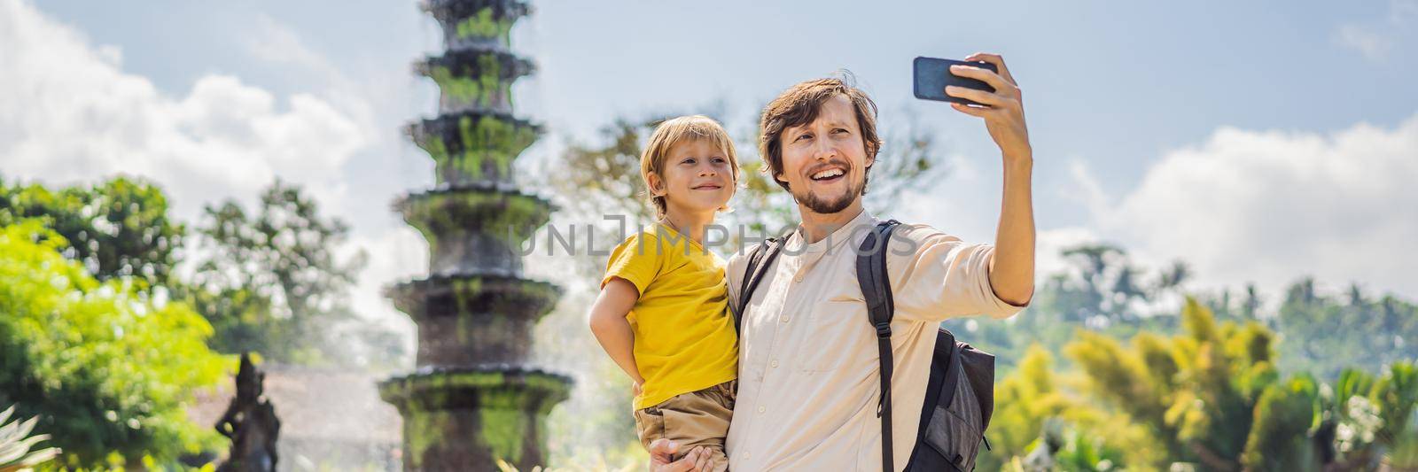 Dad and son tourists in Taman Tirtagangga, Water palace, Water park, Bali Indonesia. Honeymoon in Bali. Traveling with children concept. Kids friendly place. BANNER, LONG FORMAT
