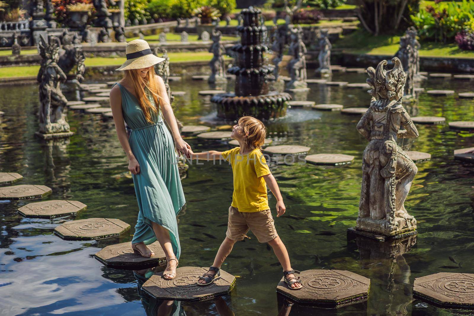 Mom and son tourists in Taman Tirtagangga, Water palace, Water park, Bali Indonesia. Honeymoon in Bali. Traveling with children concept. Kids friendly place.