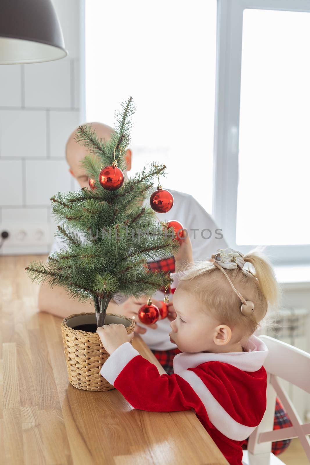 Child with cochlear implant hearing aid having fun with father and small christmas tree - diversity and deafness treatment and medical innovative technologies by Satura86