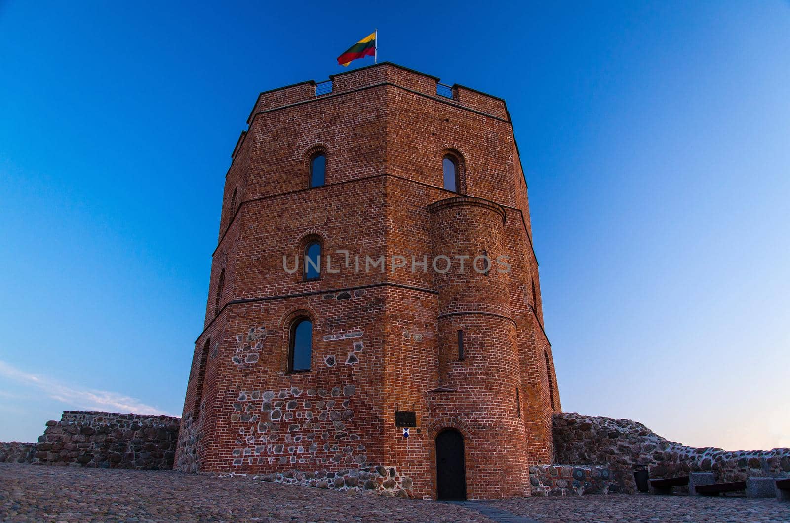 Medieval old Castle Tower Of Gediminas (Gedimino) on hill with Lithuanian national flag above at sunset, Vilnius, Lithuania