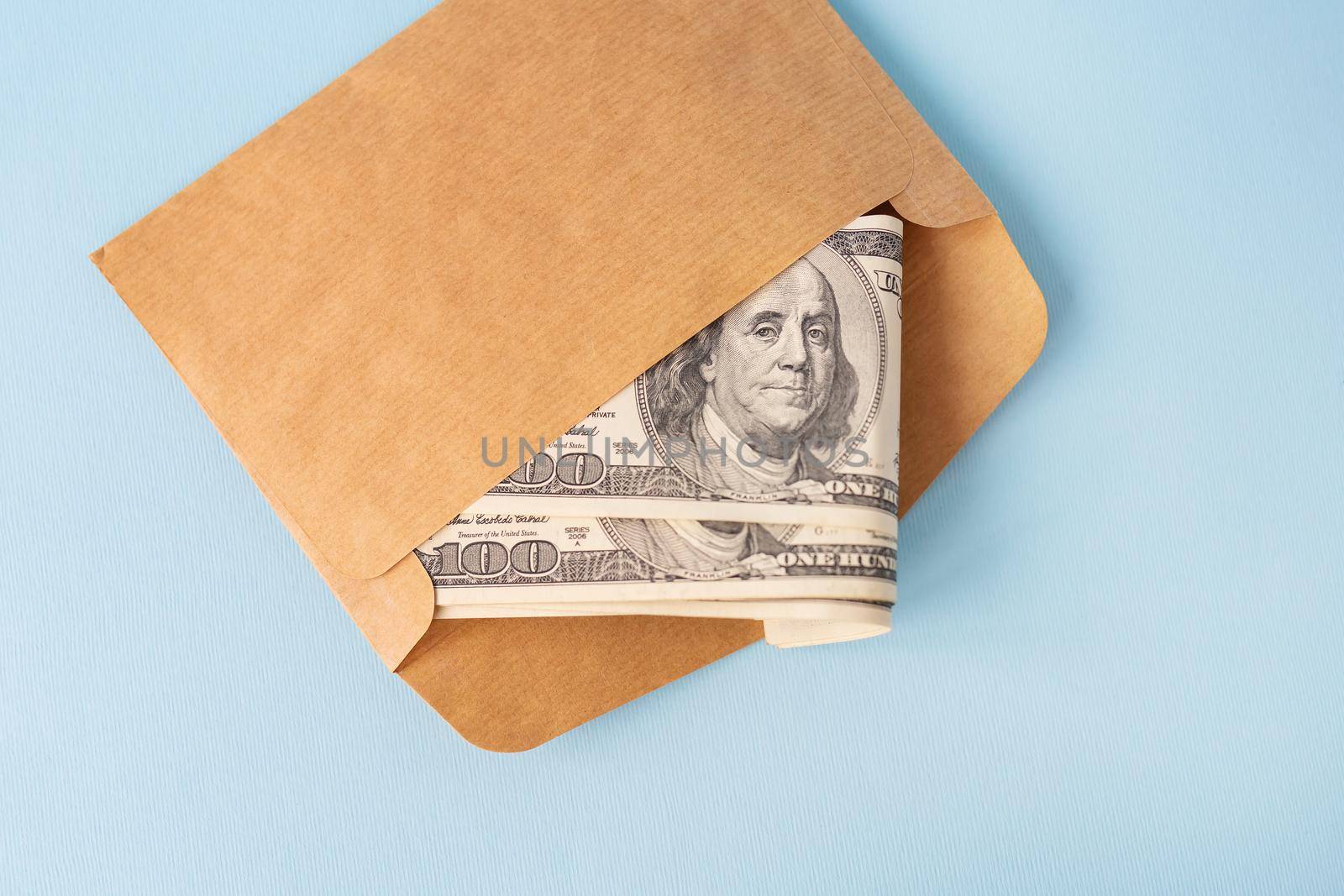 Stash of money in dollar bills coming out of an envelope on a blue background. The concept of salary, bribe, loan, debt, win. by sfinks