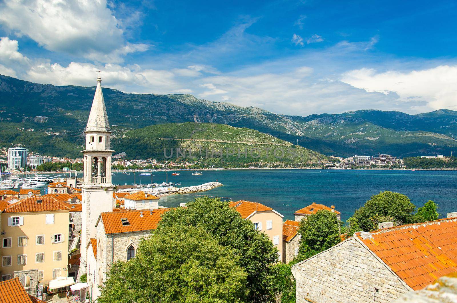 Panoramic view from citadel fortress of Old town Budva with medieval buildings, red tiled roofs, chapel of Saint Ivan church, marine, bay, range of mountains and Adriatic Riviera, Montenegro