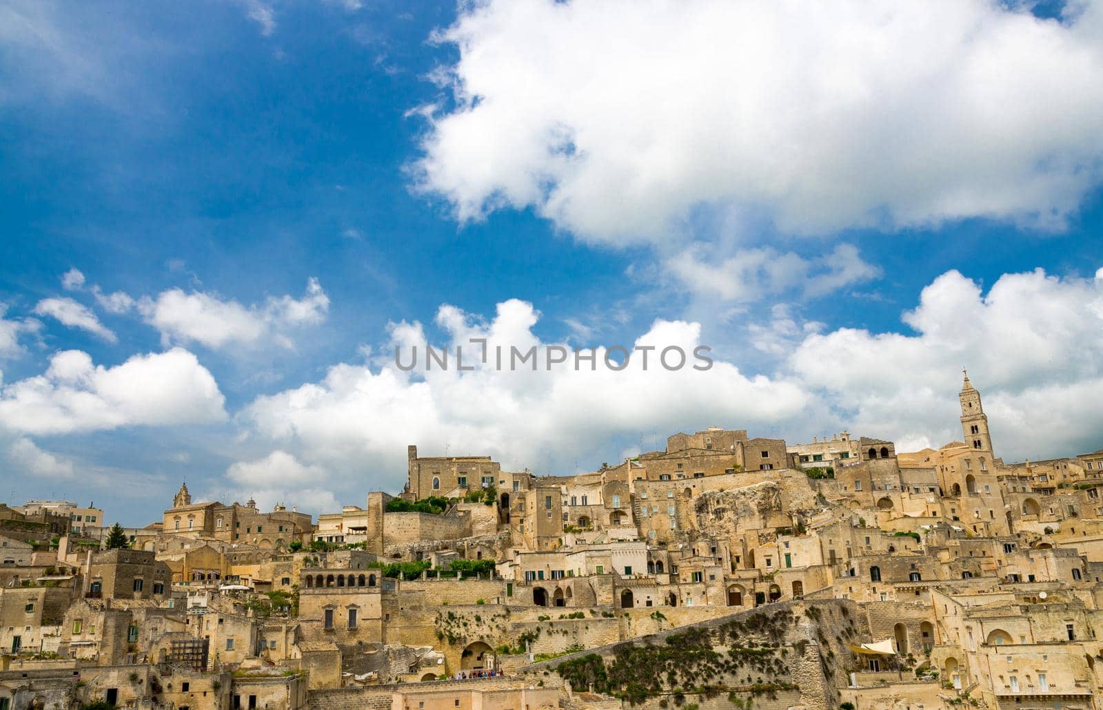 Sassi di Matera panoramic view of historical centre Sasso Caveoso of old ancient town with rock cave houses in front of blue sky and white clouds, UNESCO World Heritage, Basilicata, Southern Italy