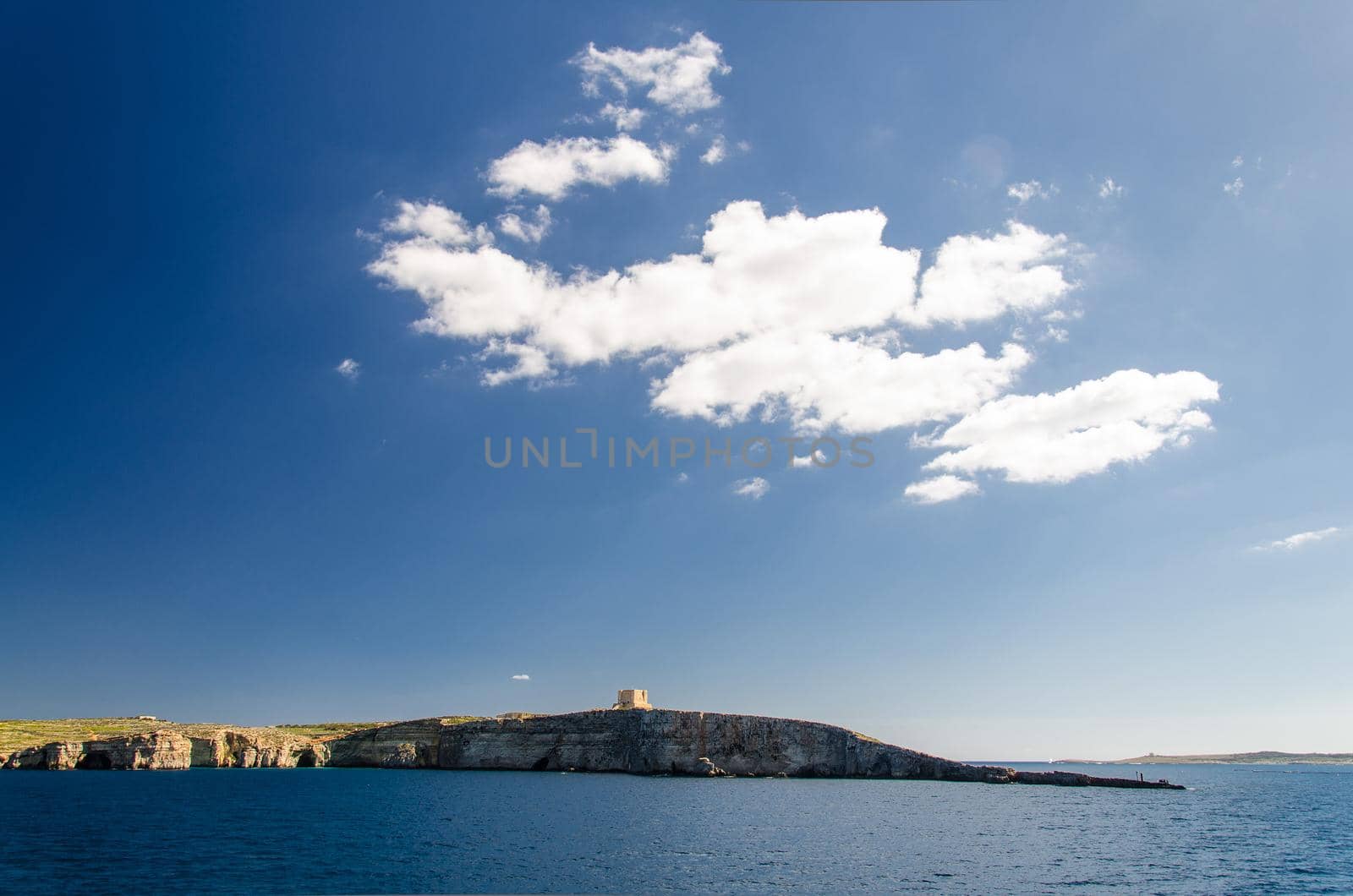 Blue sky and white clouds above Saint Mary's Tower bastioned watchtower on the island of Comino or Kemmuna of the Maltese Archipelago in the Mediterranean Sea, Malta