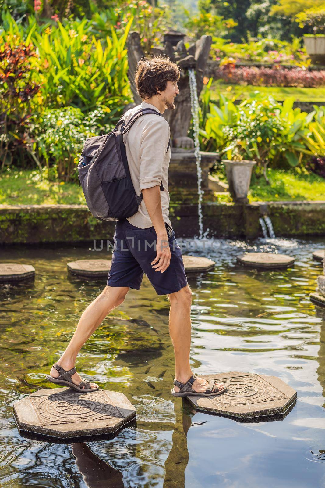 Young man tourist in Taman Tirtagangga, Water palace, Water park, Bali Indonesia.