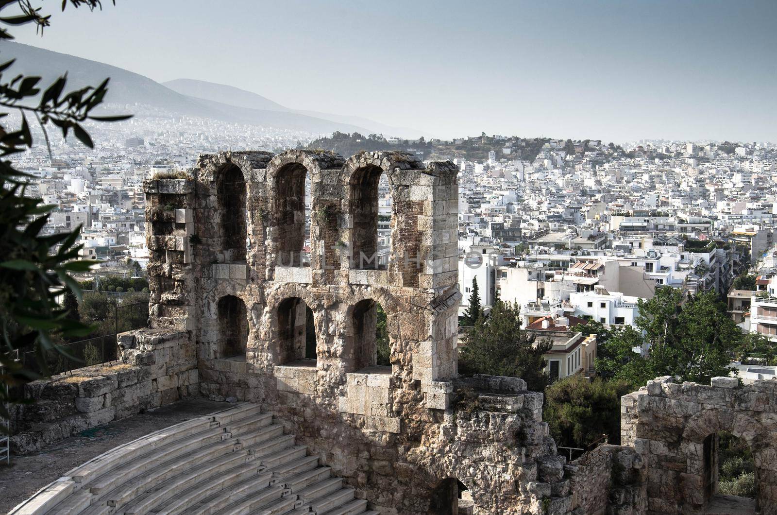 Panoramic view of white buildings city districts and The Odeon of Herodes Atticus stone theatre under Acropolis in Athens, Greece