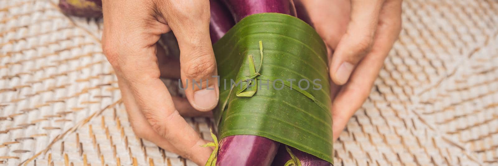 BANNER, LONG FORMAT Eco-friendly product packaging concept. Eggplant wrapped in a banana leaf, as an alternative to a plastic bag. Zero waste concept. Alternative packaging.