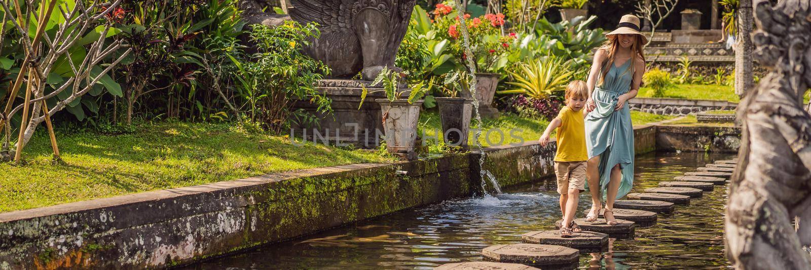 Mom and son tourists in Taman Tirtagangga, Water palace, Water park, Bali Indonesia. Traveling with children concept. Kids friendly place BANNER, LONG FORMAT by galitskaya