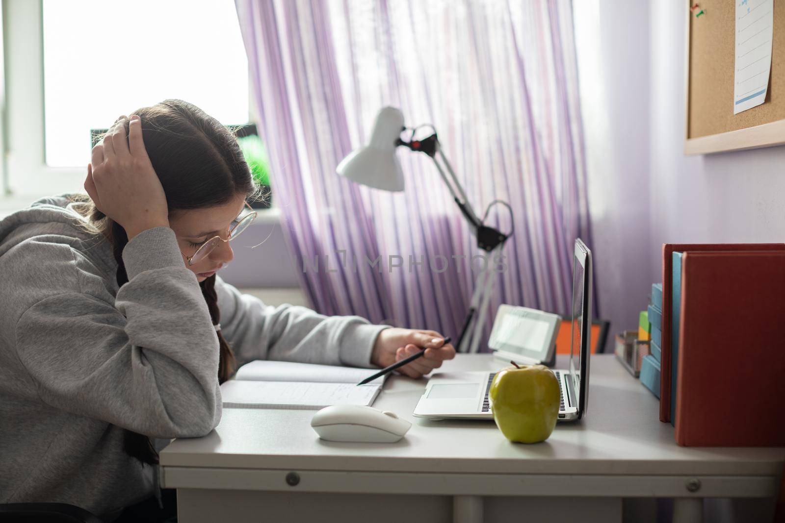 A student is thinking and thinking about how to solve a complicated assignment she received from school to do at home. A diligent student. Remote learning at home.