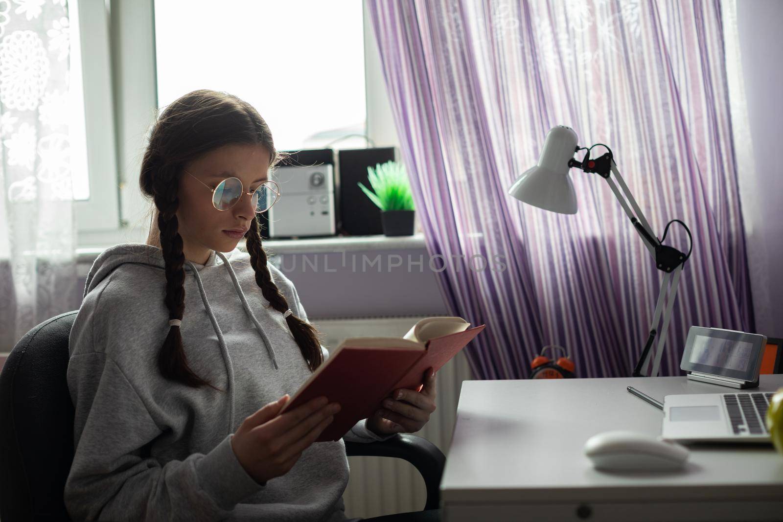 A young girl reads a school book. Gaining knowledge through school reading. A capable student. A young girl with braids.