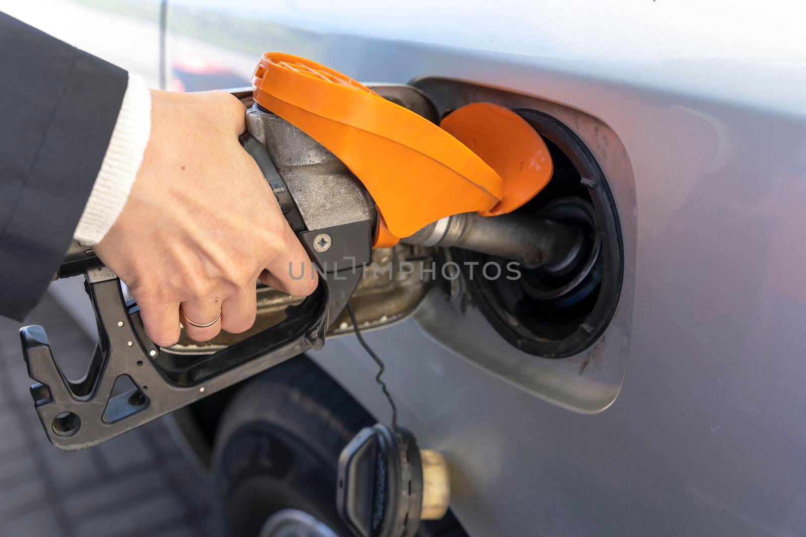 a woman's hand holds a refueling gun in the neck of the tank of the car. the girl refuels the car by audiznam2609