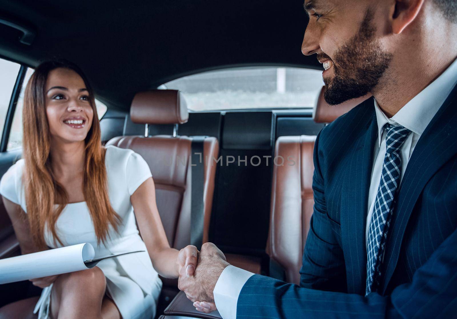 Business handshake to close the success agreement in back seat car