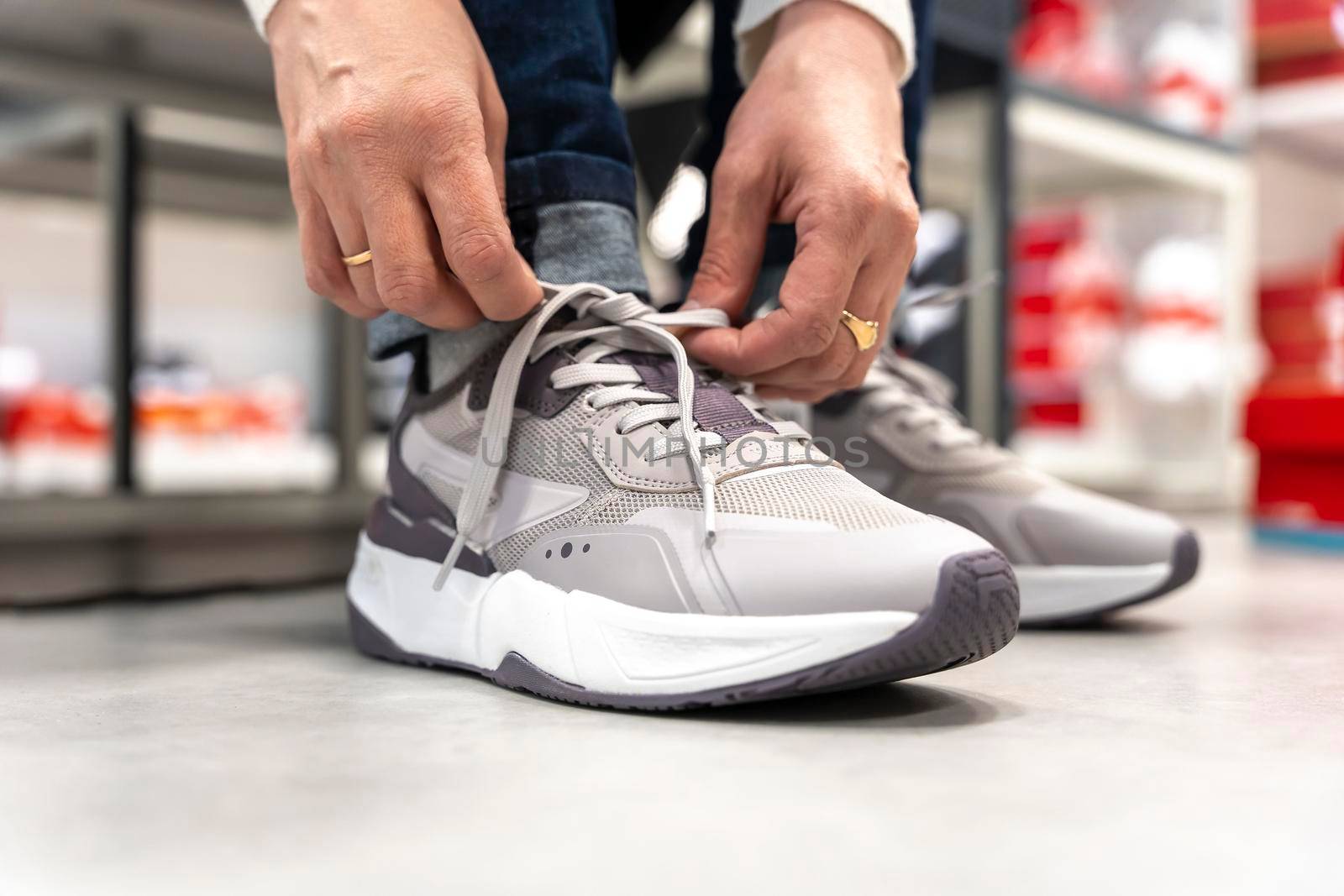 a girl tries on new sneakers in a sportswear store while sitting on a bench. a girl buys sports shoes.