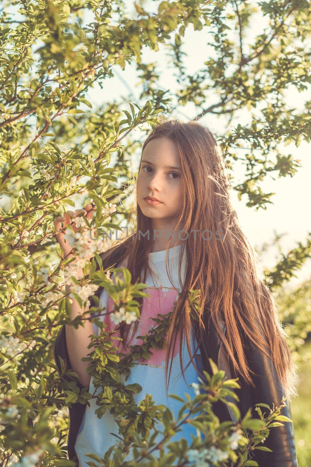 Portrait of a beautiful happy teenage girl outdoors in spring. A girl poses in a blooming spring garden.