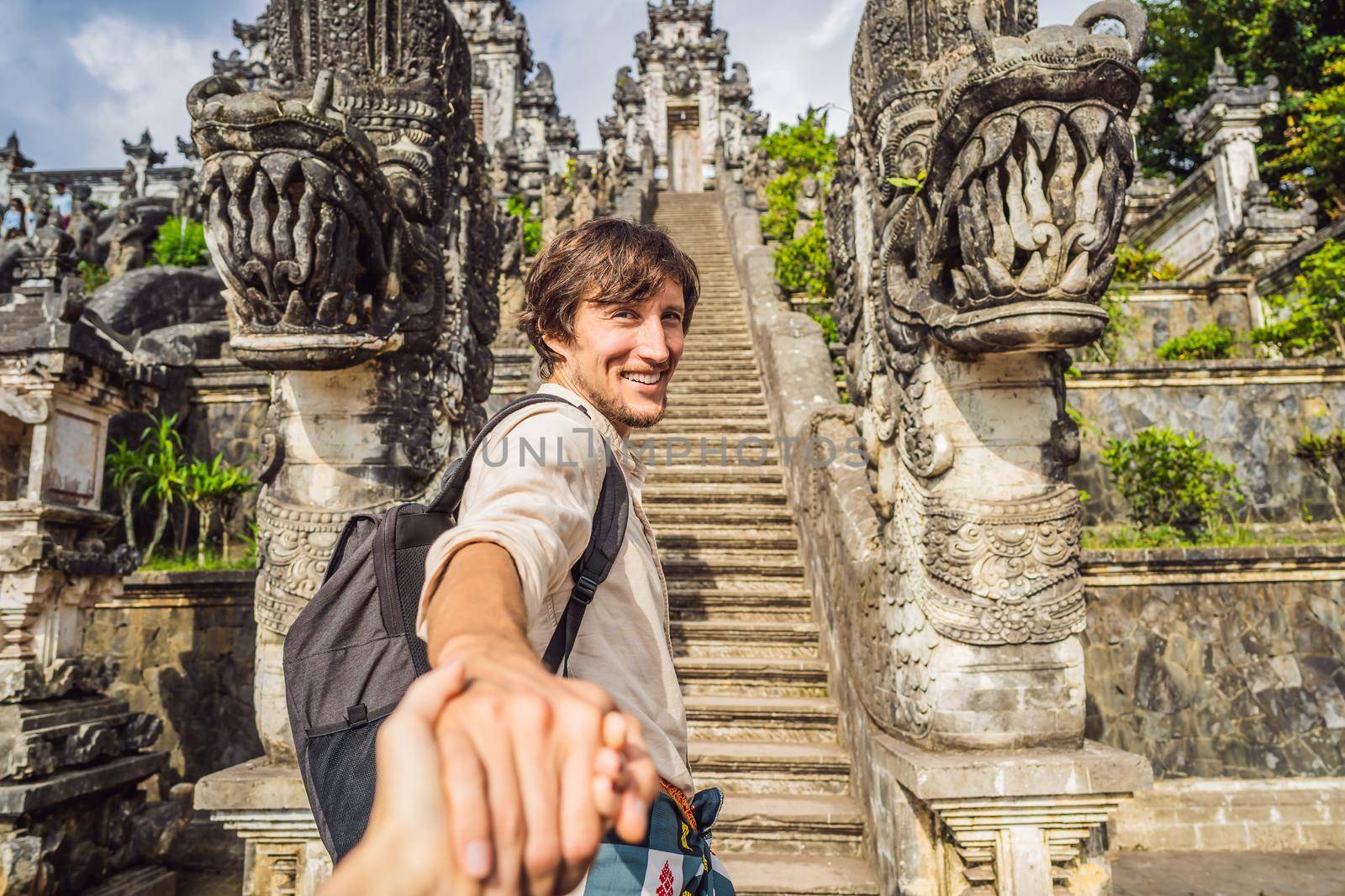 follow me photo. Young man tourist on background of Three stone ladders in beautiful Pura Lempuyang Luhur temple. Summer landscape with stairs to temple. Paduraksa portals marking entrance to middle sanctum jaba tengah of Pura Penataran Agung, Bali.