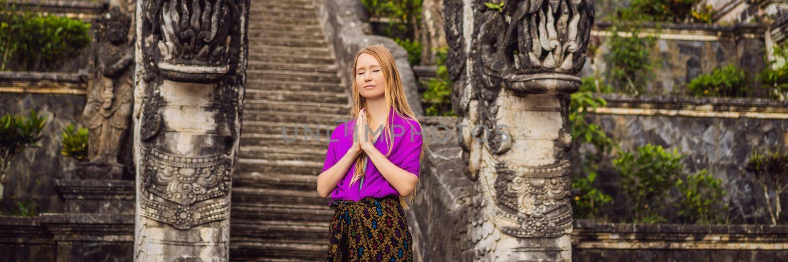 BANNER, LONG FORMAT Young woman tourist on background of Three stone ladders in beautiful Pura Lempuyang Luhur temple. Summer landscape with stairs to temple. Paduraksa portals marking entrance to middle sanctum jaba tengah of Pura Penataran Agung, Bali by galitskaya