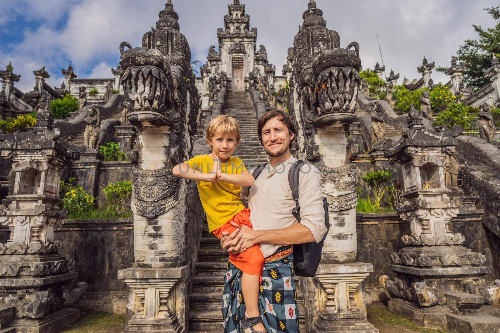 Dad and son tourists on background of Three stone ladders in beautiful Pura Lempuyang Luhur temple.Paduraksa portals marking entrance to middle sanctum jaba tengah of Pura Penataran Agung, Bali. Traveling with children concept. Kids friendly place.