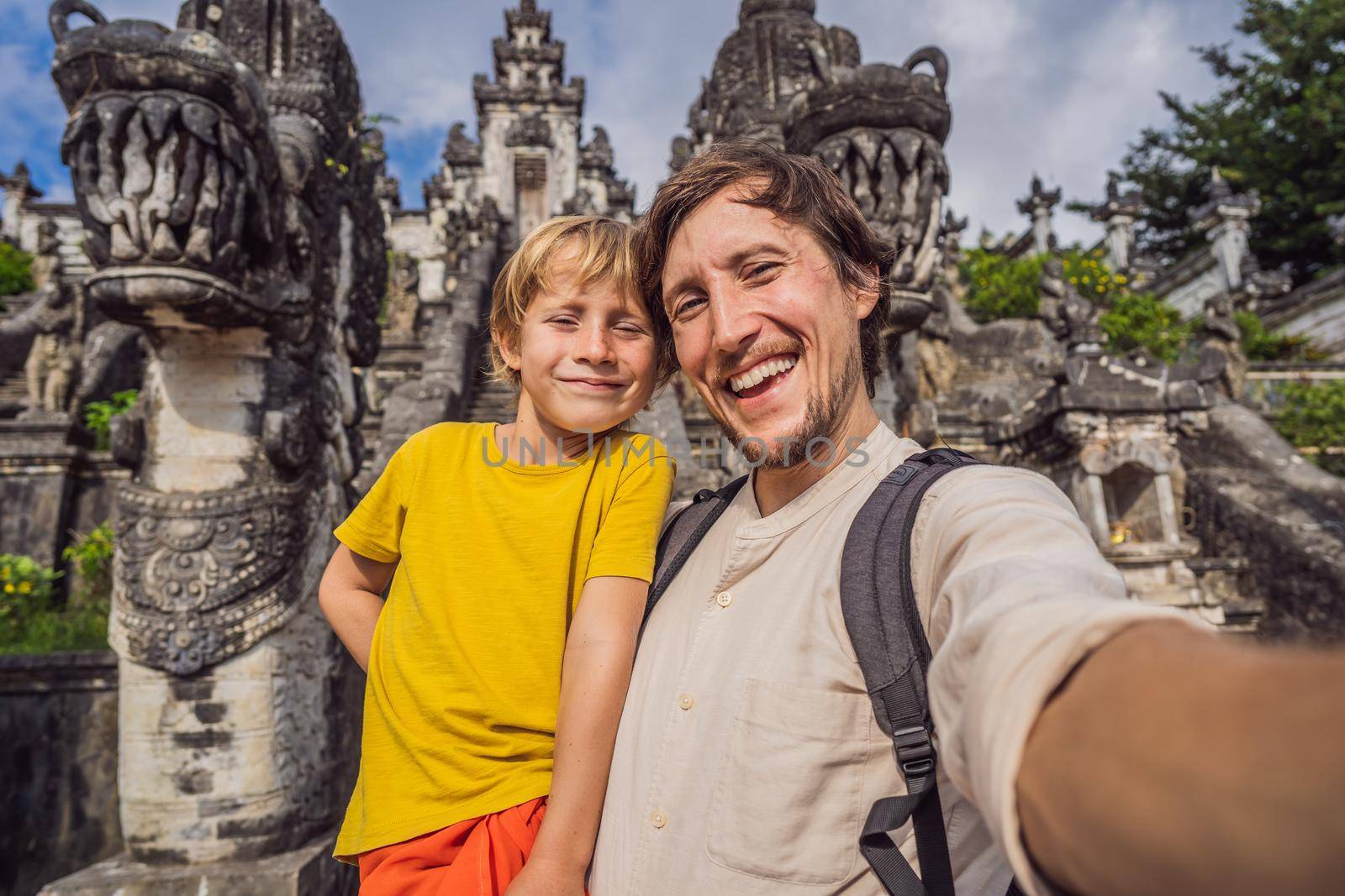 Dad and son tourists on background of Three stone ladders in beautiful Pura Lempuyang Luhur temple.Paduraksa portals marking entrance to middle sanctum jaba tengah of Pura Penataran Agung, Bali. Traveling with children concept. Kids friendly place.