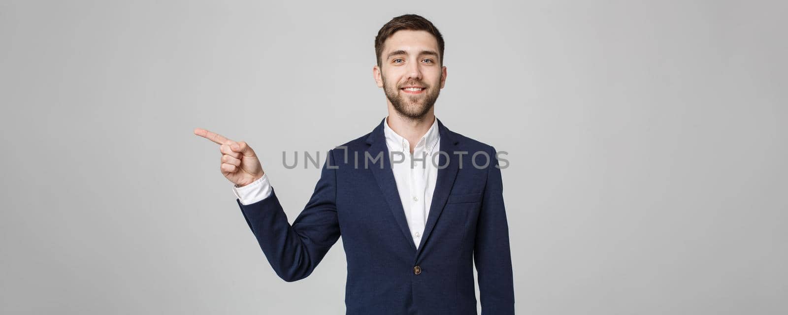 Young successful businessman pointing direction with finger over dark grey background. Copy space.