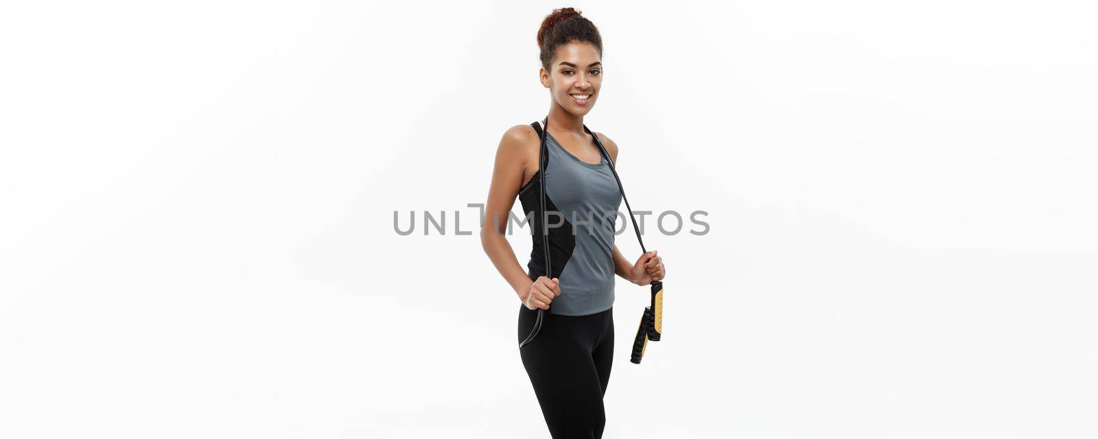 Sport, training, lifestyle and Fitness concept - portrait of beautiful happy African American woman exercising with jumping rope. Isolated on white studio background