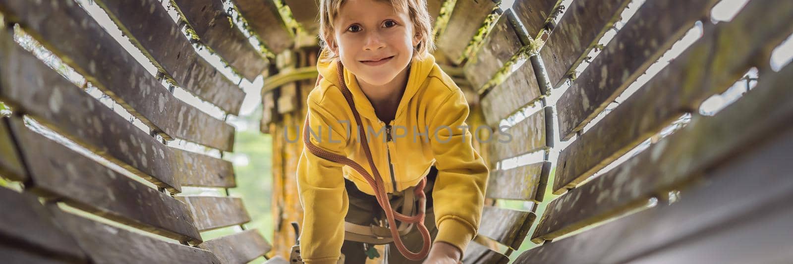 Little boy in a rope park. Active physical recreation of the child in the fresh air in the park. Training for children. BANNER, LONG FORMAT