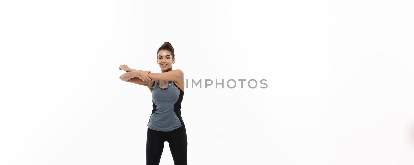 Sport, training, lifestyle and Fitness concept - Full-length portrait of beautiful happy African American woman stretching hands. Isolated on white studio background