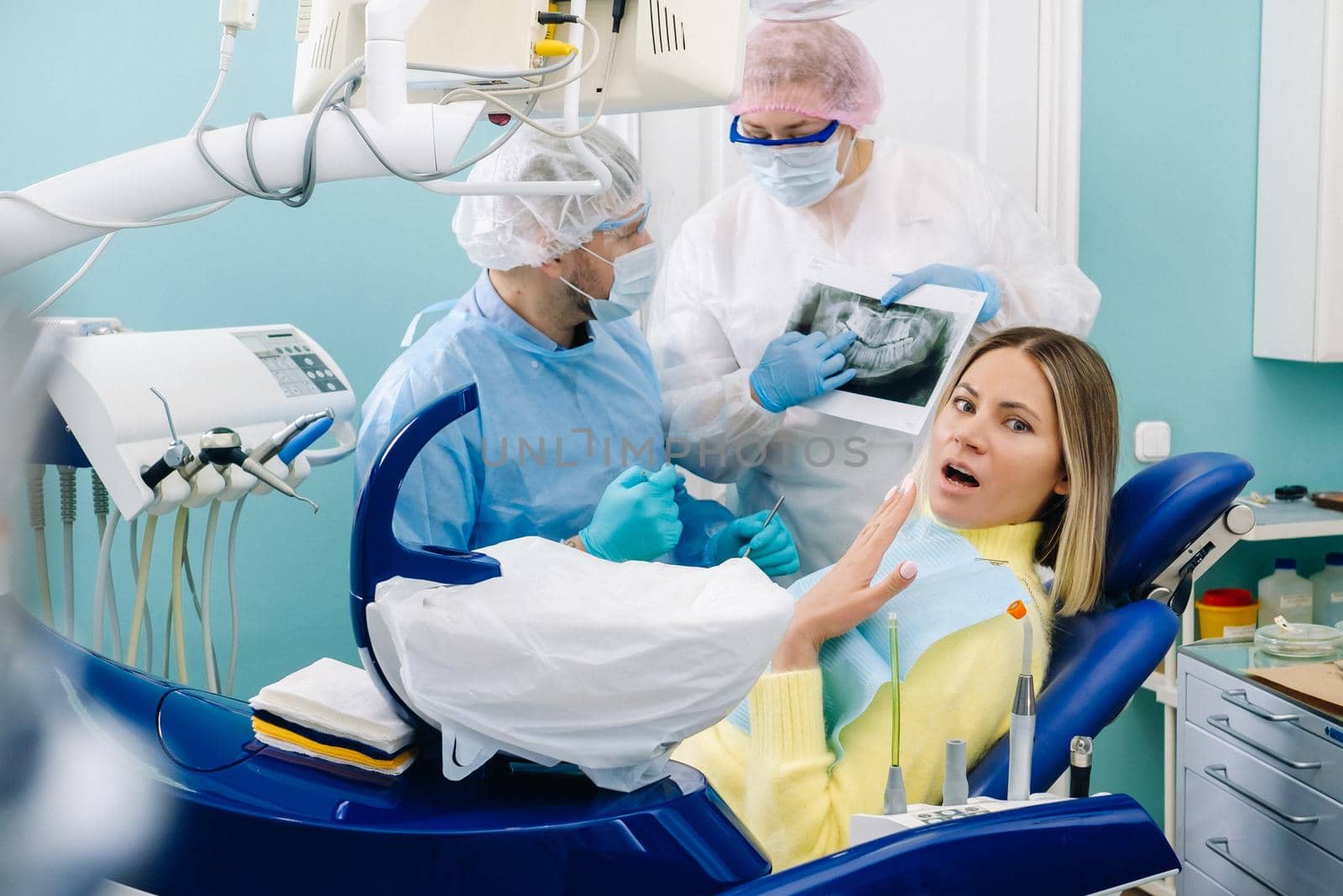 The dentist explains the details of the X-ray to his colleague, the patient is surprised by what is happening.