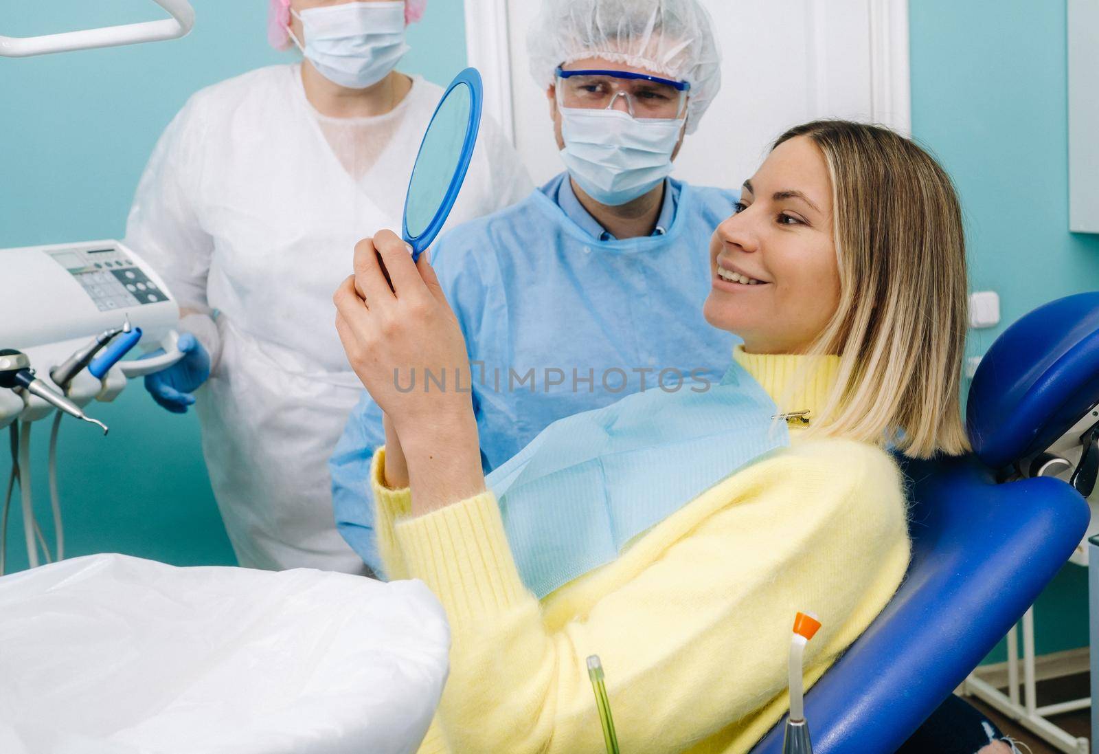 The dentist shows the client the results of his work in the mirror.
