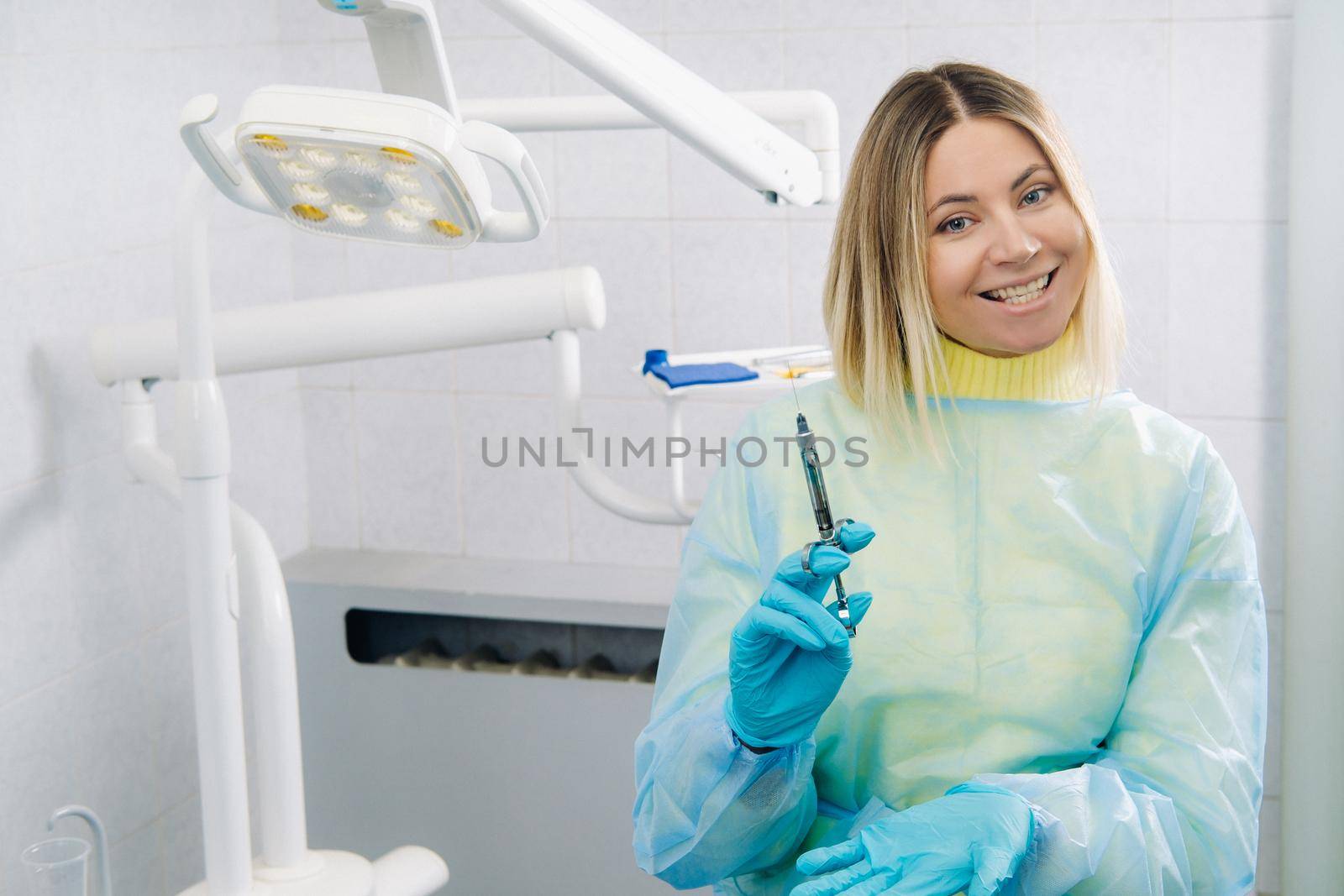 The dentist holds an injection syringe for the patient in the office by Lobachad
