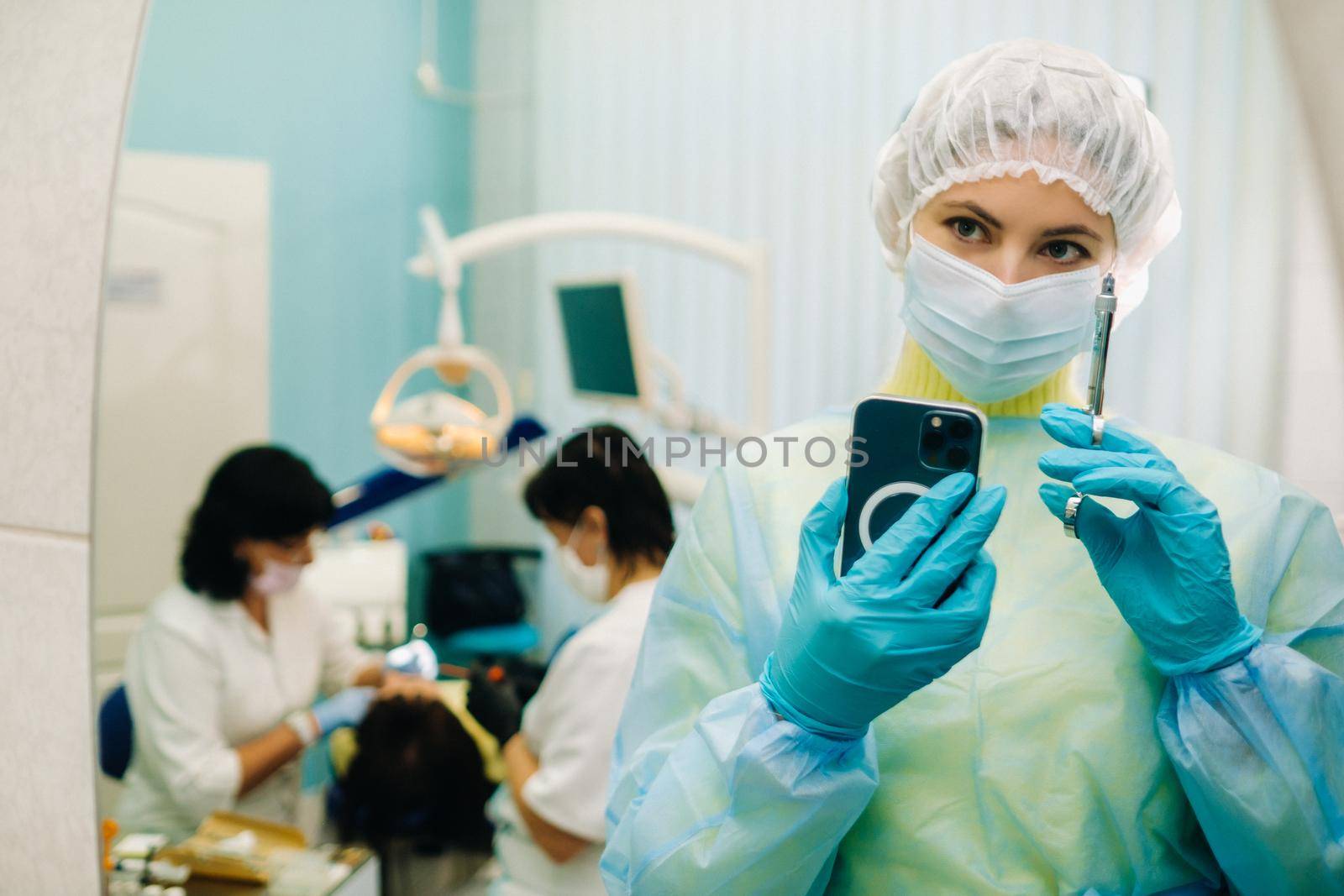 the dentist in a protective mask stands next to the patient and takes a photo after work.