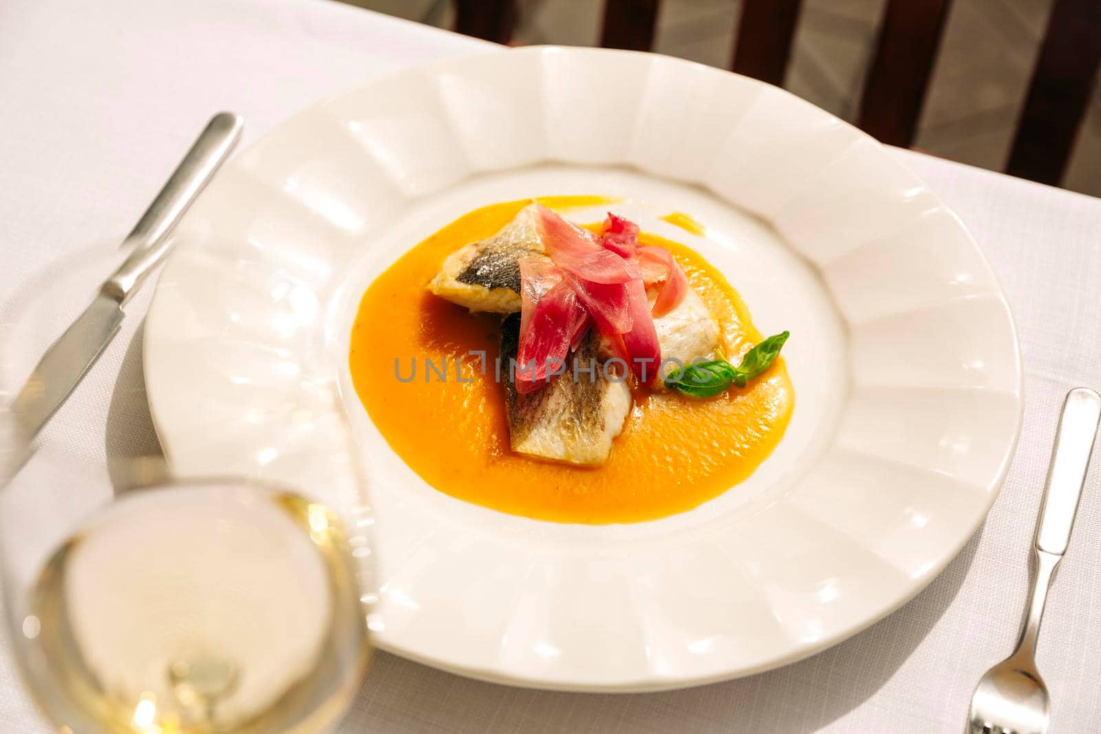 A dish in a restaurant in Venice. Sea bass steak in yellow stew with caramelized onions.