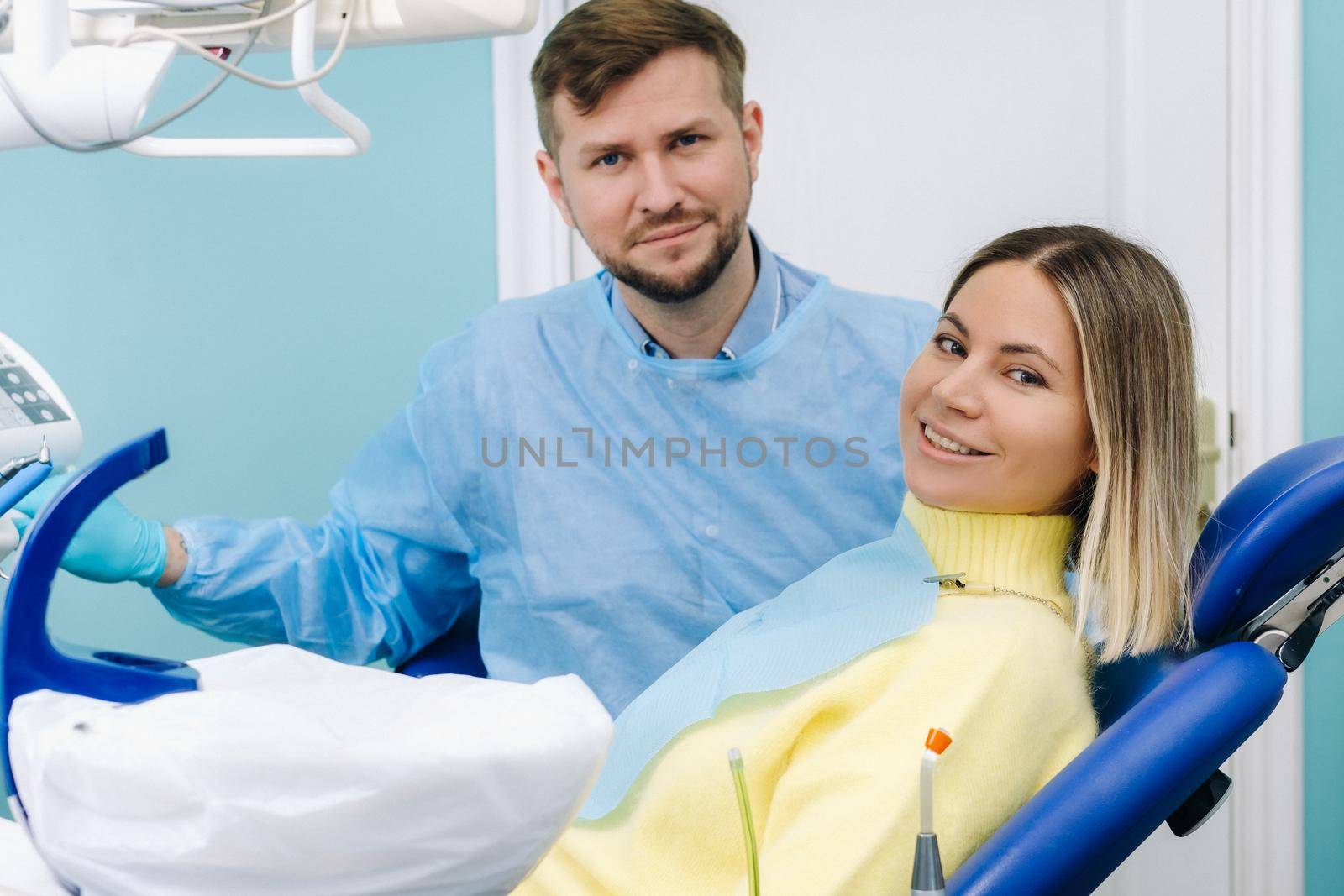 A beautiful girl patient is sitting in the dentist's office at the reception and next to the doctor.