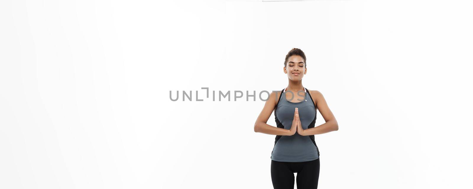 Healthy and Fitness concept - Beautiful American African lady in fitness clothing doing yoga and meditation. Isolated on white background. by Benzoix