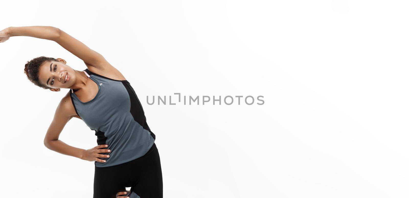 Sport, training, lifestyle and Fitness concept - portrait of beautiful happy African American woman stretching hands. Isolated on white studio background. by Benzoix