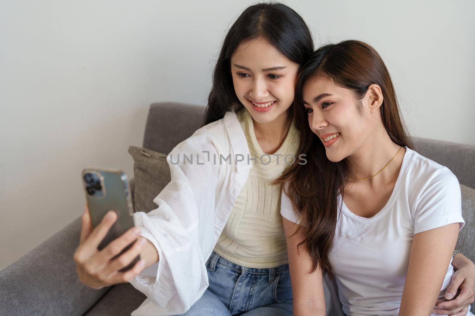 lgbtq, lgbt concept, homosexuality, portrait of two asian women enjoying together and showing love for each other while using smartphone mobile to take selfies by Manastrong