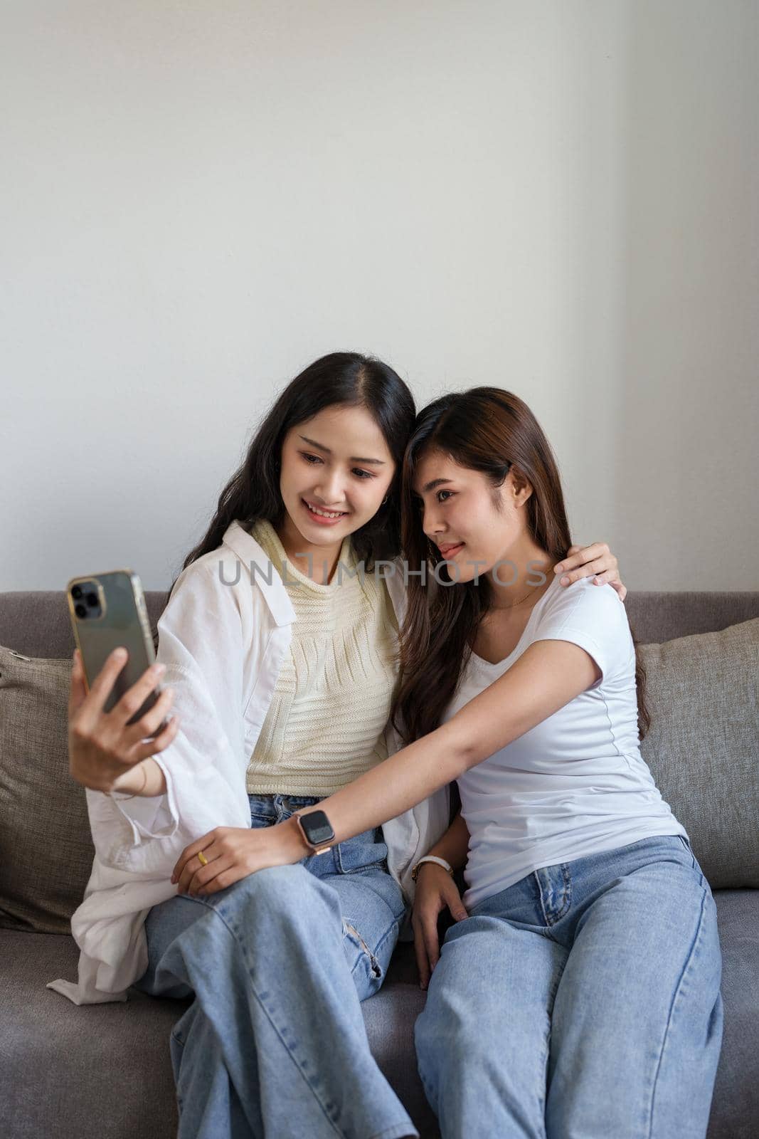 lgbtq, lgbt concept, homosexuality, portrait of two asian women enjoying together and showing love for each other while using smartphone mobile to take selfies by Manastrong