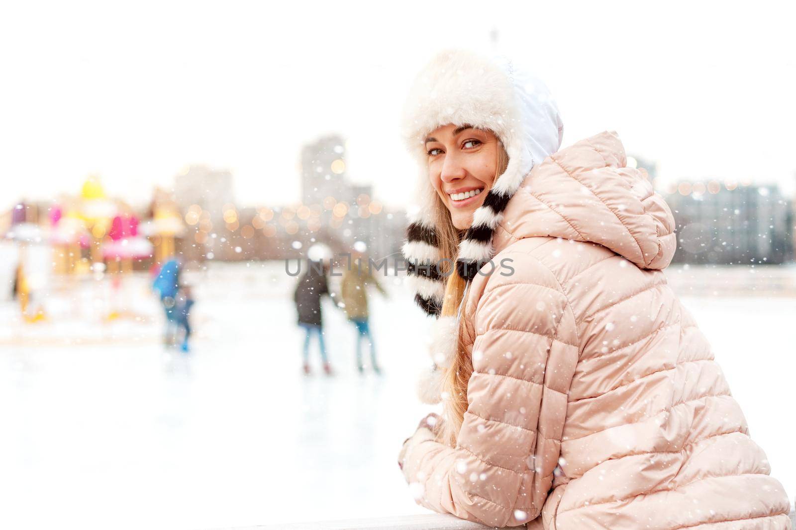 Medium shoot portrait of romantic european lady wears long stylish winter jacket and funny fluffy hat in snowy day. Outdoor photo of inspired blonde woman enjoying winter city. by andreonegin