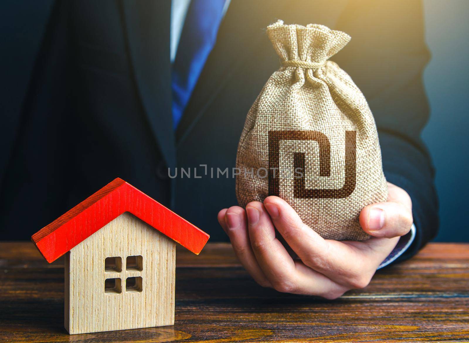 Man holds out a israeli shekel bag near the house. Home purchase, invest in real estate. Property appraisal. Favorable terms conditions, low interest rate. Bank approval for issuing a mortgage loan.