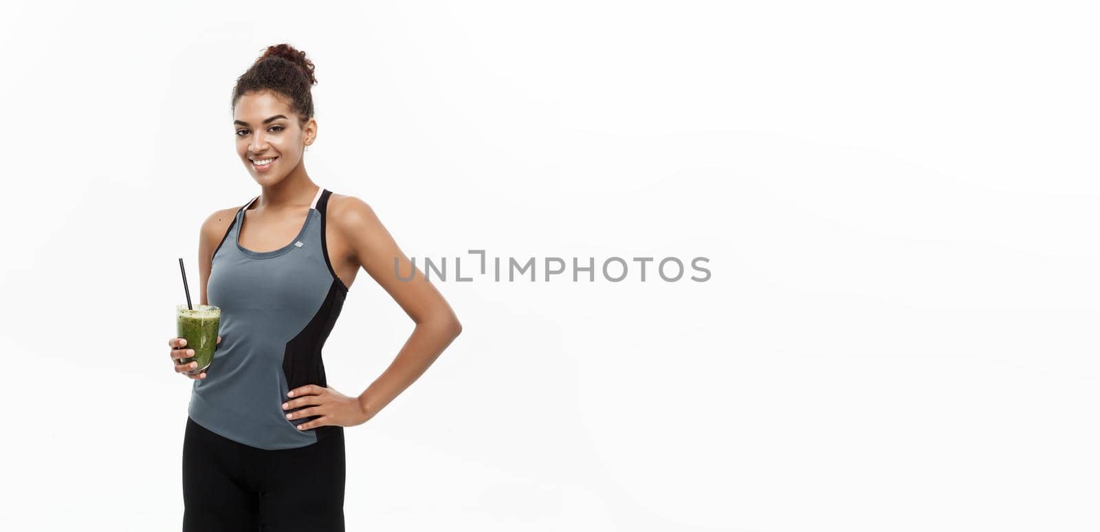 Healthy and Fitness concept - beautiful African American girl in sport clothes holding plastic water bottle after workout. Isolated on white studio background by Benzoix