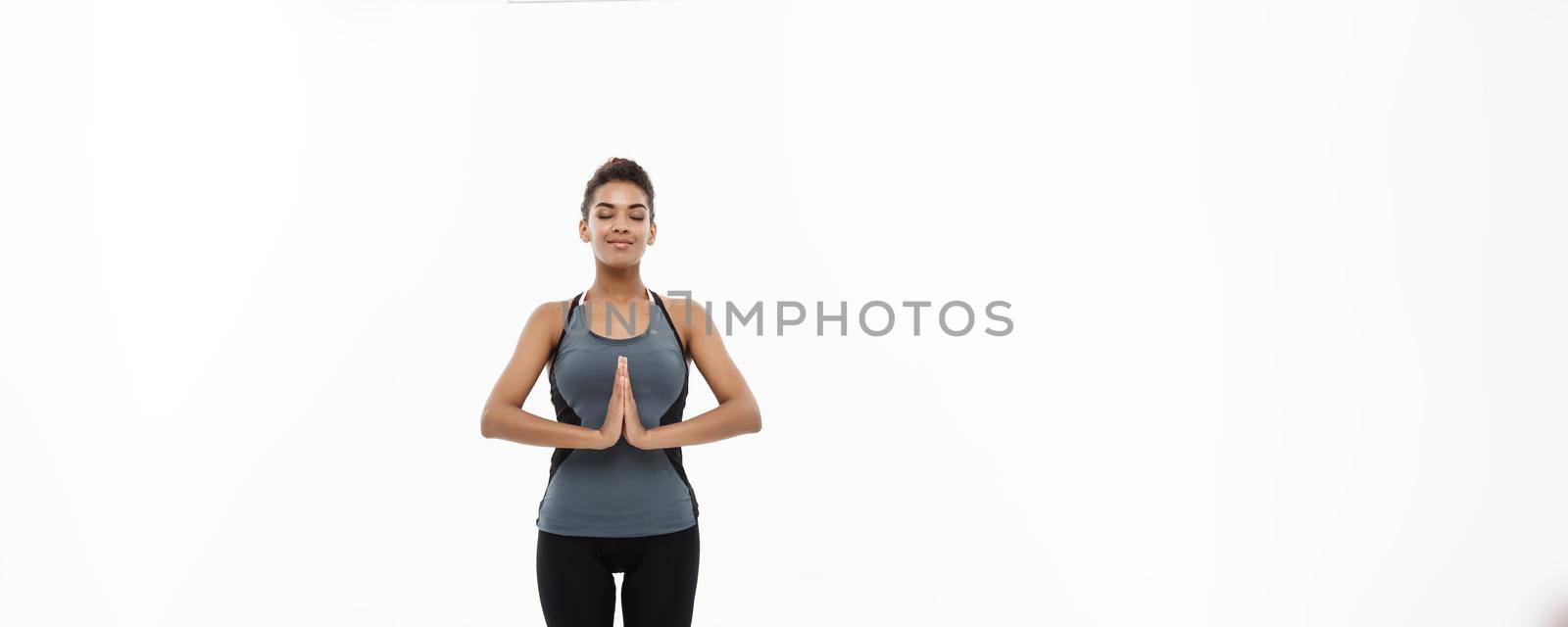 Healthy and Fitness concept - Beautiful American African lady in fitness clothing doing yoga and meditation. Isolated on white background