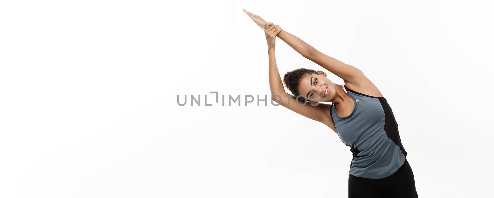 Sport, training, lifestyle and Fitness concept - portrait of beautiful happy African American woman stretching hands. Isolated on white studio background. by Benzoix