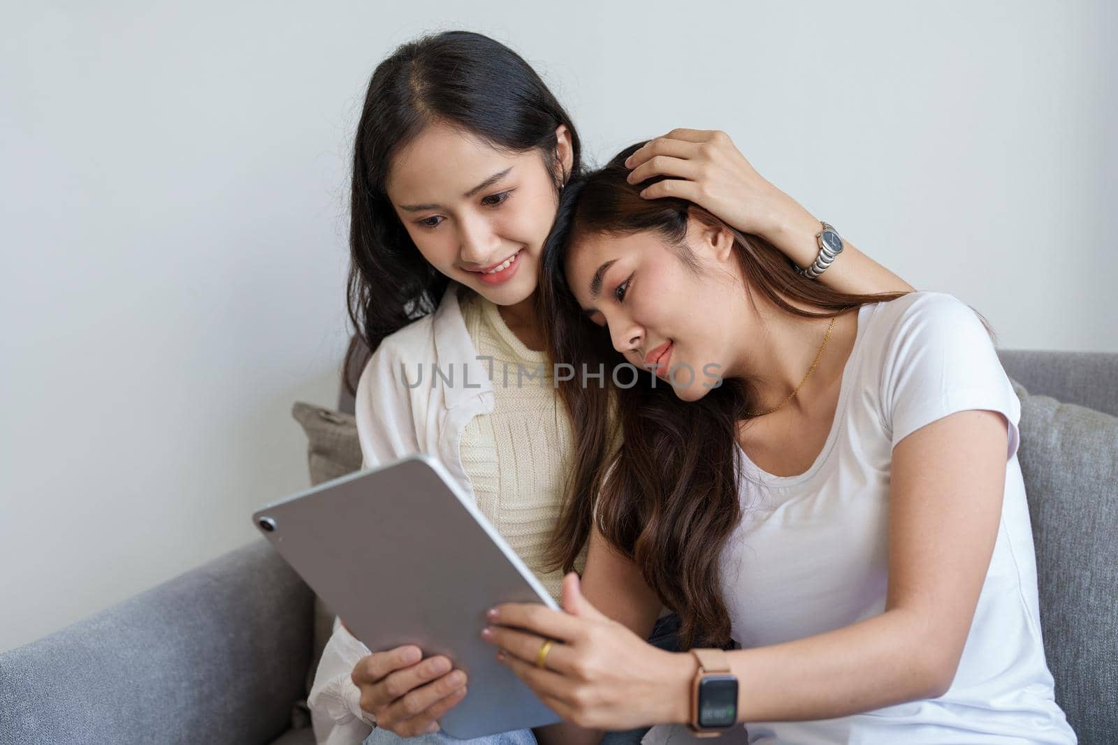 lgbtq, lgbt concept, homosexuality, portrait of two asian women enjoying together and showing love for each other while using tablet by Manastrong