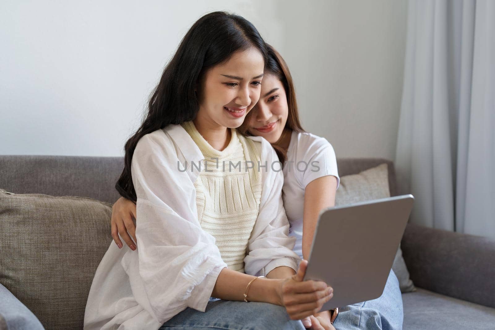 lgbtq, lgbt concept, homosexuality, portrait of two asian women enjoying together and showing love for each other while using tablet by Manastrong