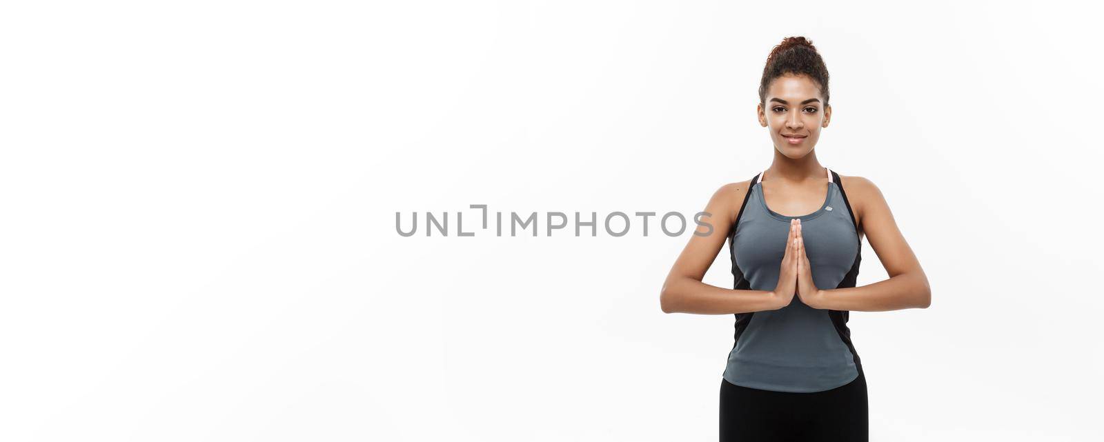 Healthy and Fitness concept - Beautiful American African lady in fitness clothing doing yoga and meditation. Isolated on white background